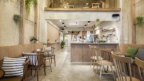 A café with wooden furniture, a central island, and hanging plants. - Vann Bangkok Boutique House (Bangkok)