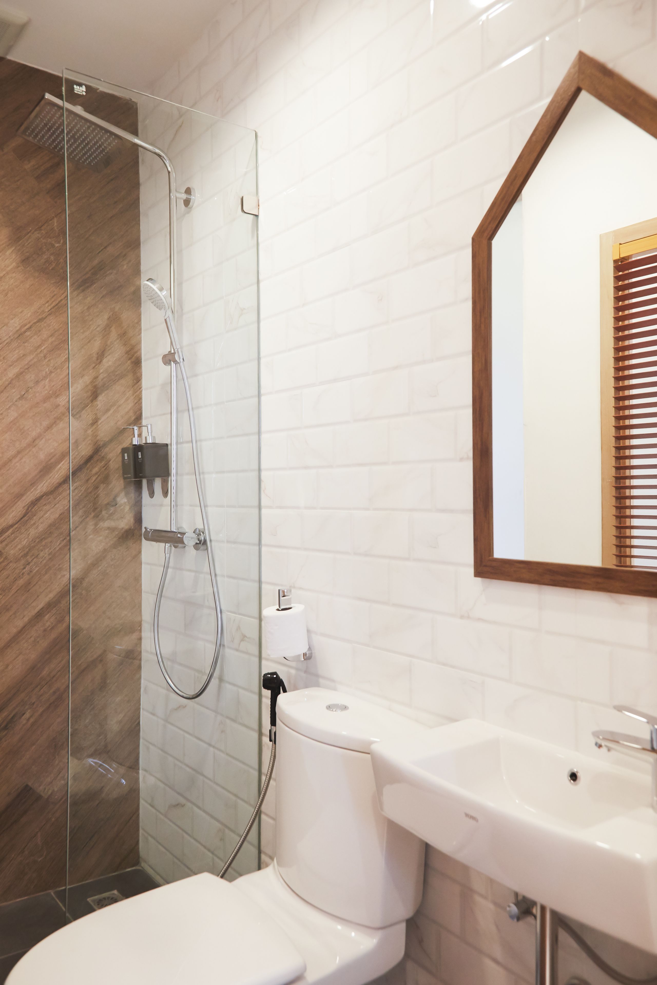 A modern bathroom with a glass-enclosed shower, a white toilet, and a sink with a mirror above it.