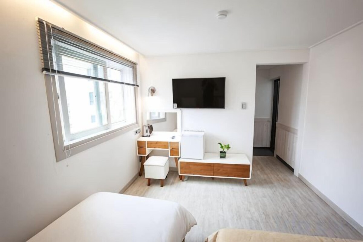 Un dormitorio moderno con una cama, una mesita de noche y un televisor montado en la pared.