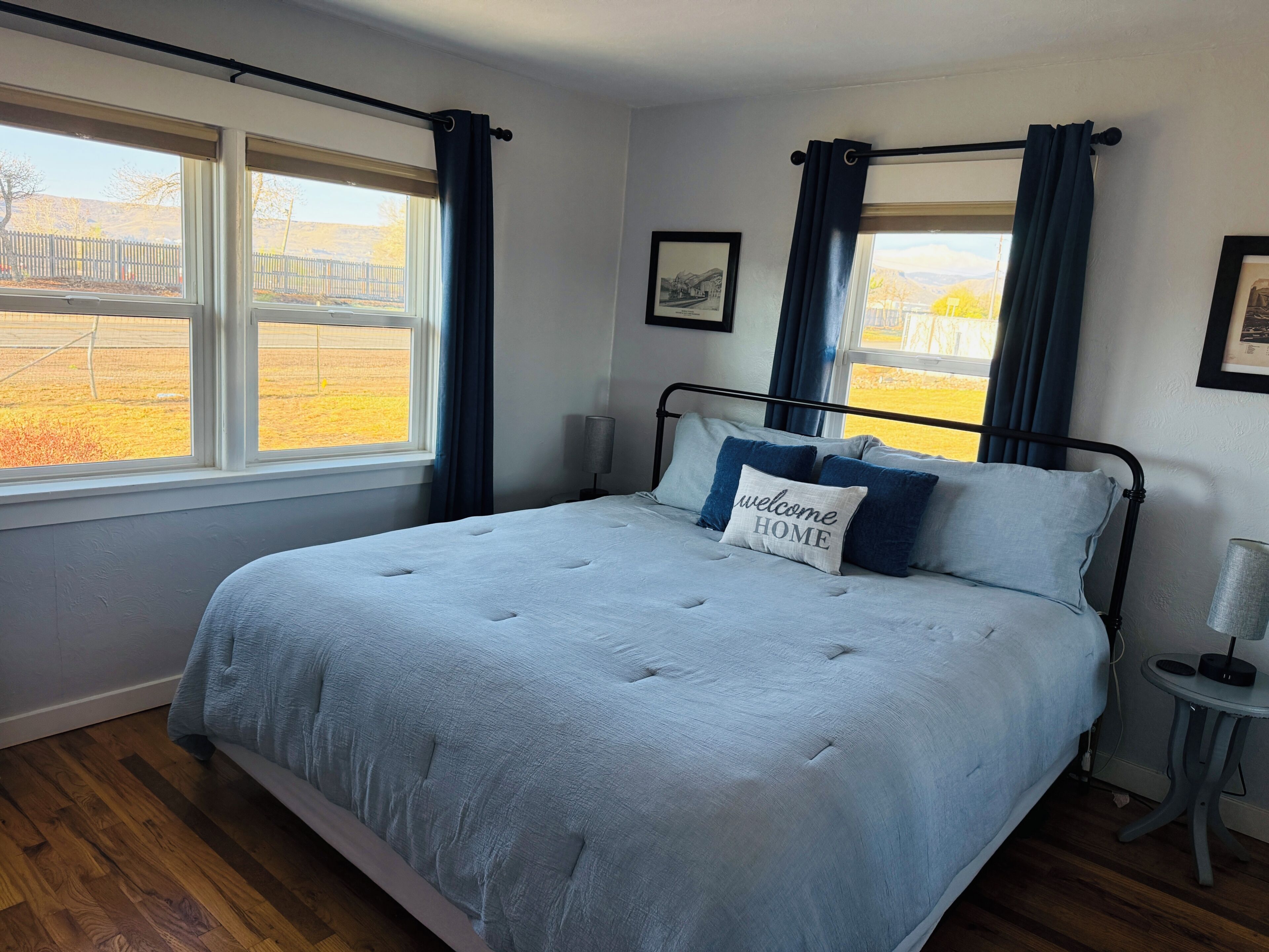 A bedroom with a bed, a bedside table, a lamp, and a window with curtains.