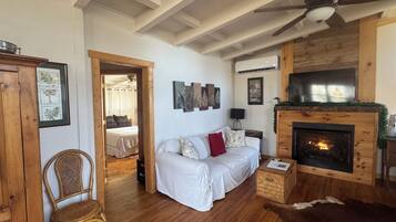 Un salon chaleureux avec une cheminée, un canapé, un plancher en bois et un ventilateur de plafond.