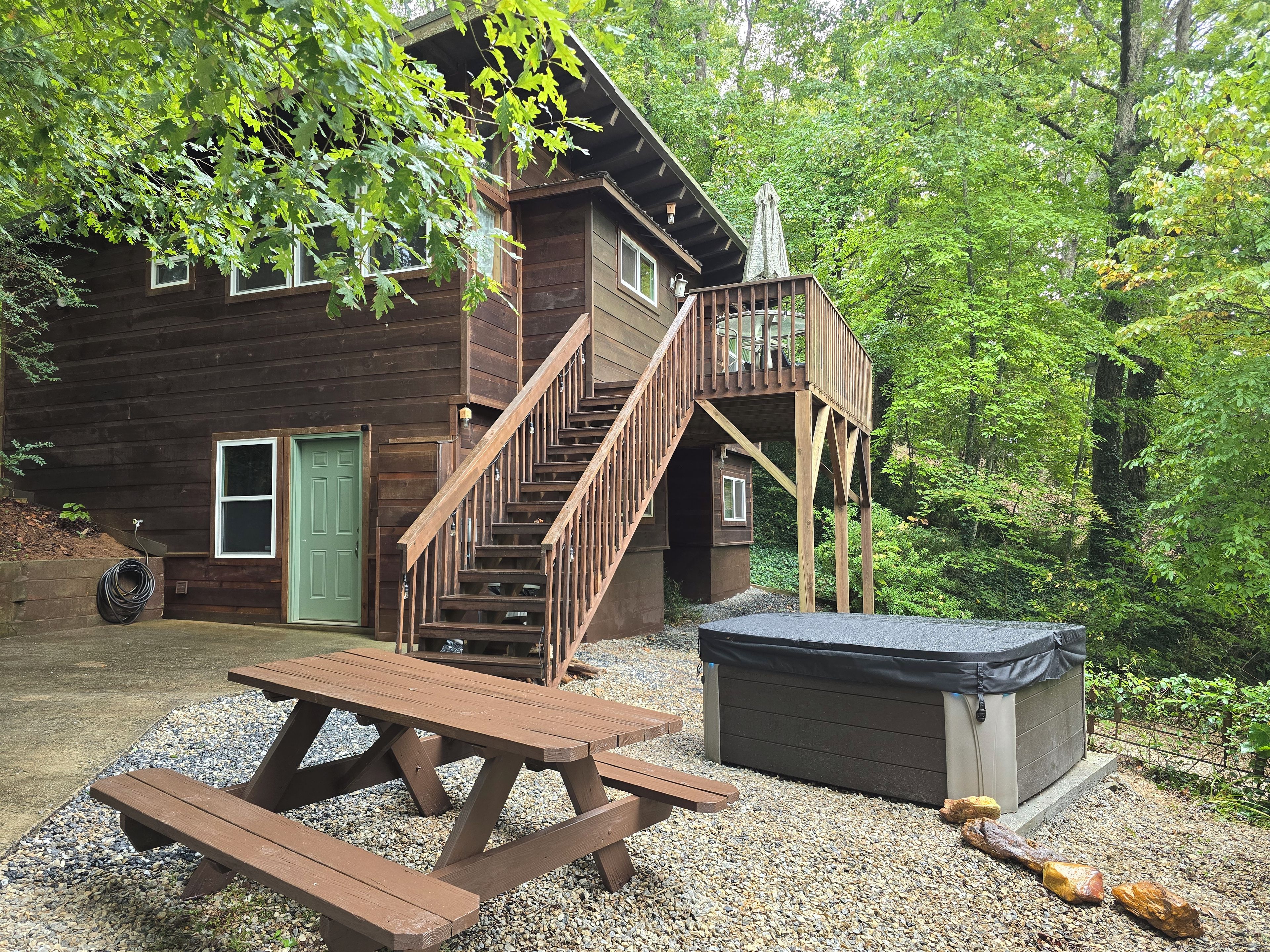 Eine Holzhütte mit einer Holzterrasse, einer Treppe und einem Picknicktisch.