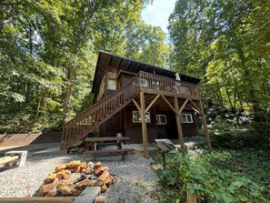 A wooden cabin with a deck and a fire pit.