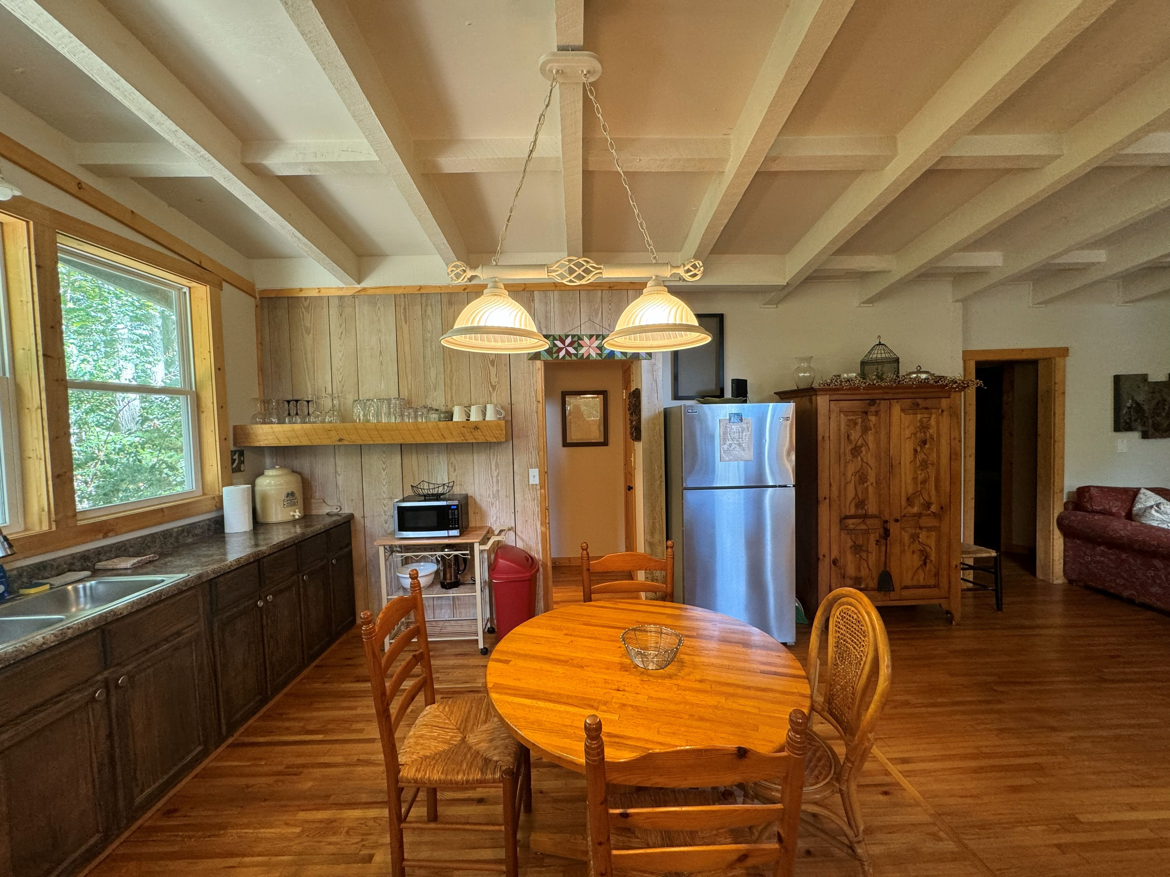 A kitchen with wooden cabinets, a stainless steel refrigerator, a microwave, and a dining table with chairs.
