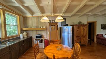 A kitchen with wooden cabinets, a stainless steel refrigerator, a microwave, and a dining table with chairs.