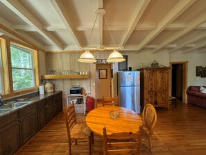 A kitchen with wooden cabinets, a stainless steel refrigerator, a microwave, and a dining table with chairs. - Elk Ridge - cherokee casino GSMNP (Whittier)