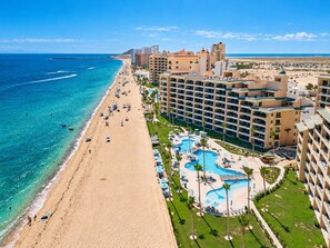 Ein Strandhotel mit Poolbereich, direktem Zugang zum Strand und mehreren Gebäuden.