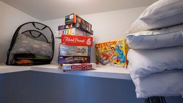 A stack of board games on a shelf, a mesh bag, and a pillow.