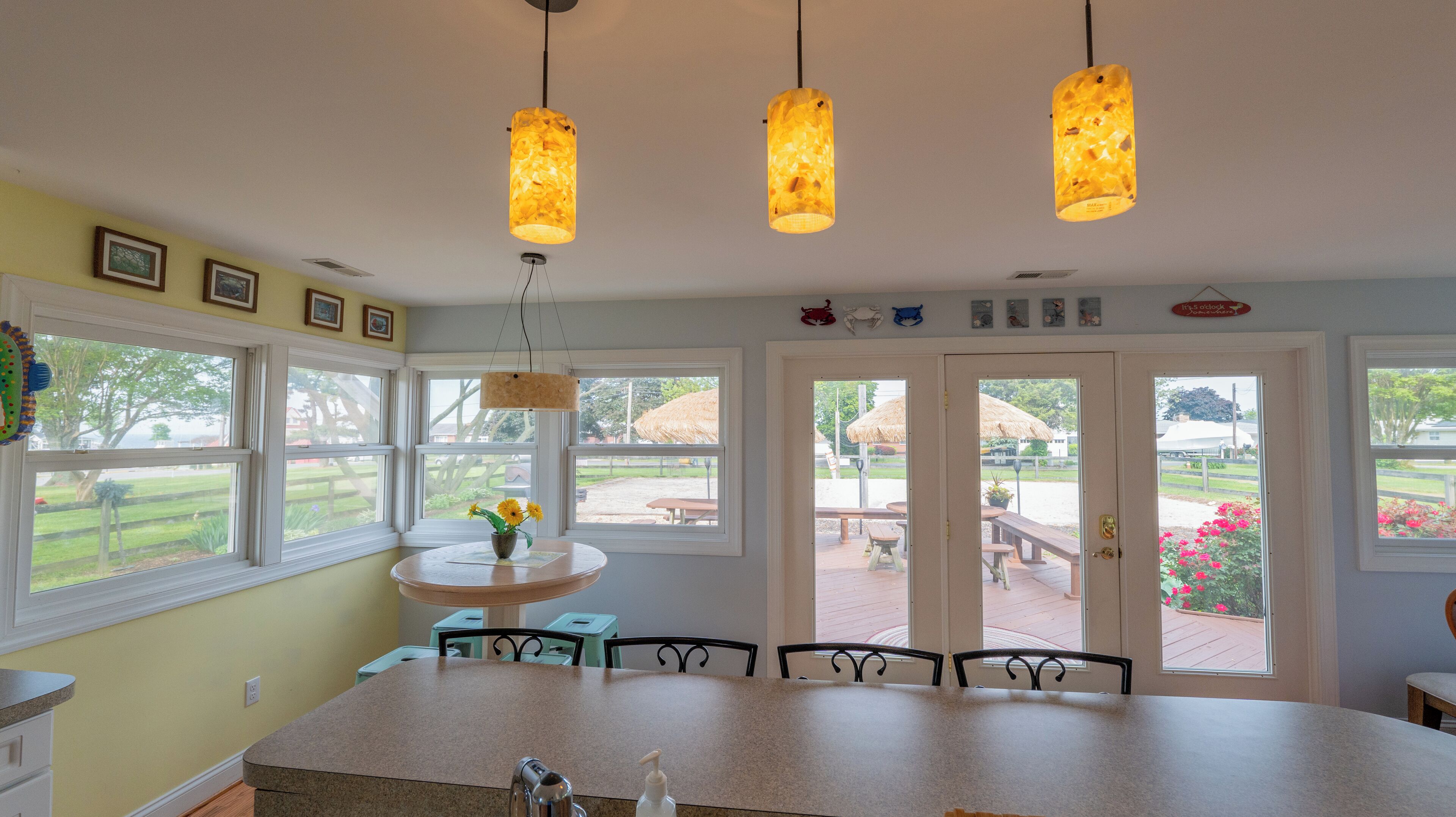 A kitchen with a large island, pendant lights, and a view of the outdoor patio through large windows.