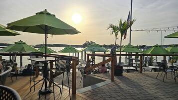 An outdoor seating area with tables and chairs, umbrellas, and a view of the water.