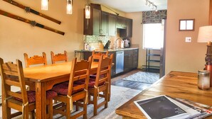 A dining area with a wooden table and chairs, a kitchen in the background, and a window providing natural light. - Remodeled Townhome in Excellent Location.Pool &Gym (Frisco)