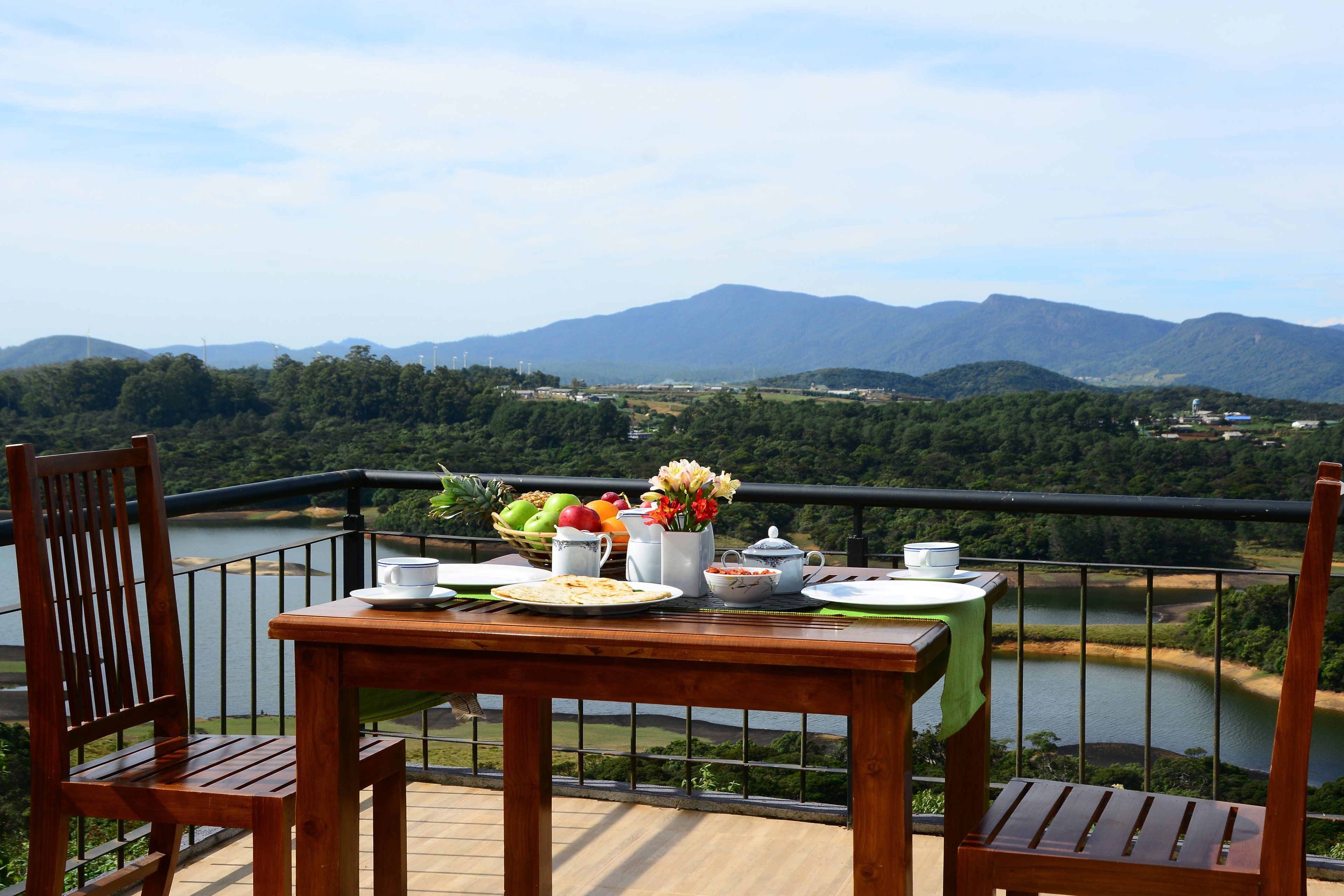 A wooden table with breakfast items and a view of a lake and mountains.