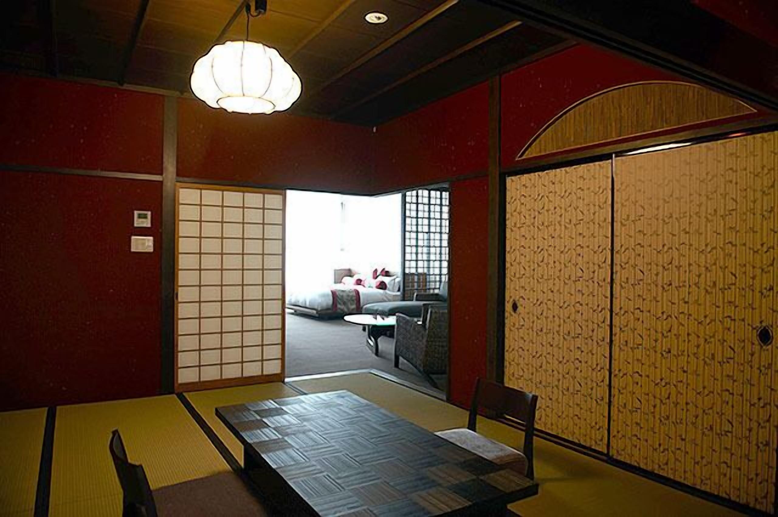 Una habitación tradicional japonesa con suelo de tatami, una mesa baja y un puertas correderas.