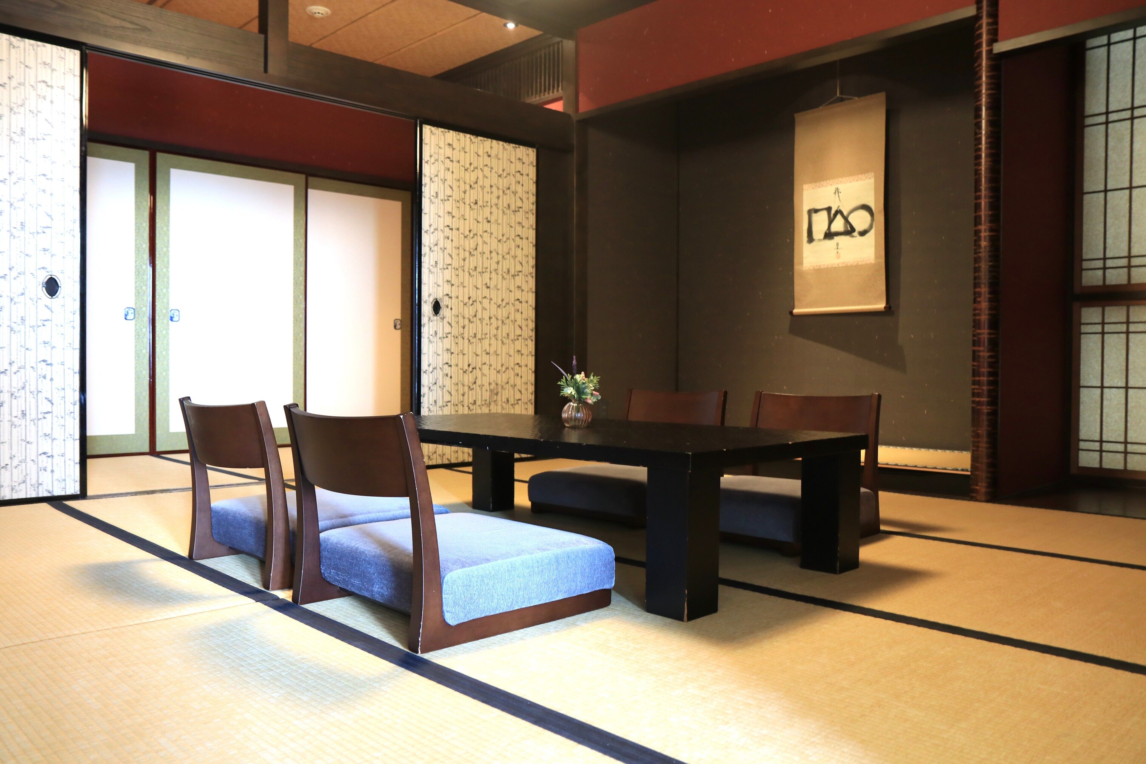 Una habitación japonesa tradicional con suelo de tatami, una mesa baja y sillas de madera.