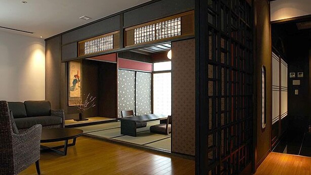 A traditional Japanese-style room with tatami flooring, a low table, a sofa, and a bookshelf. - KIZASHI THE SUITE (Kyoto)