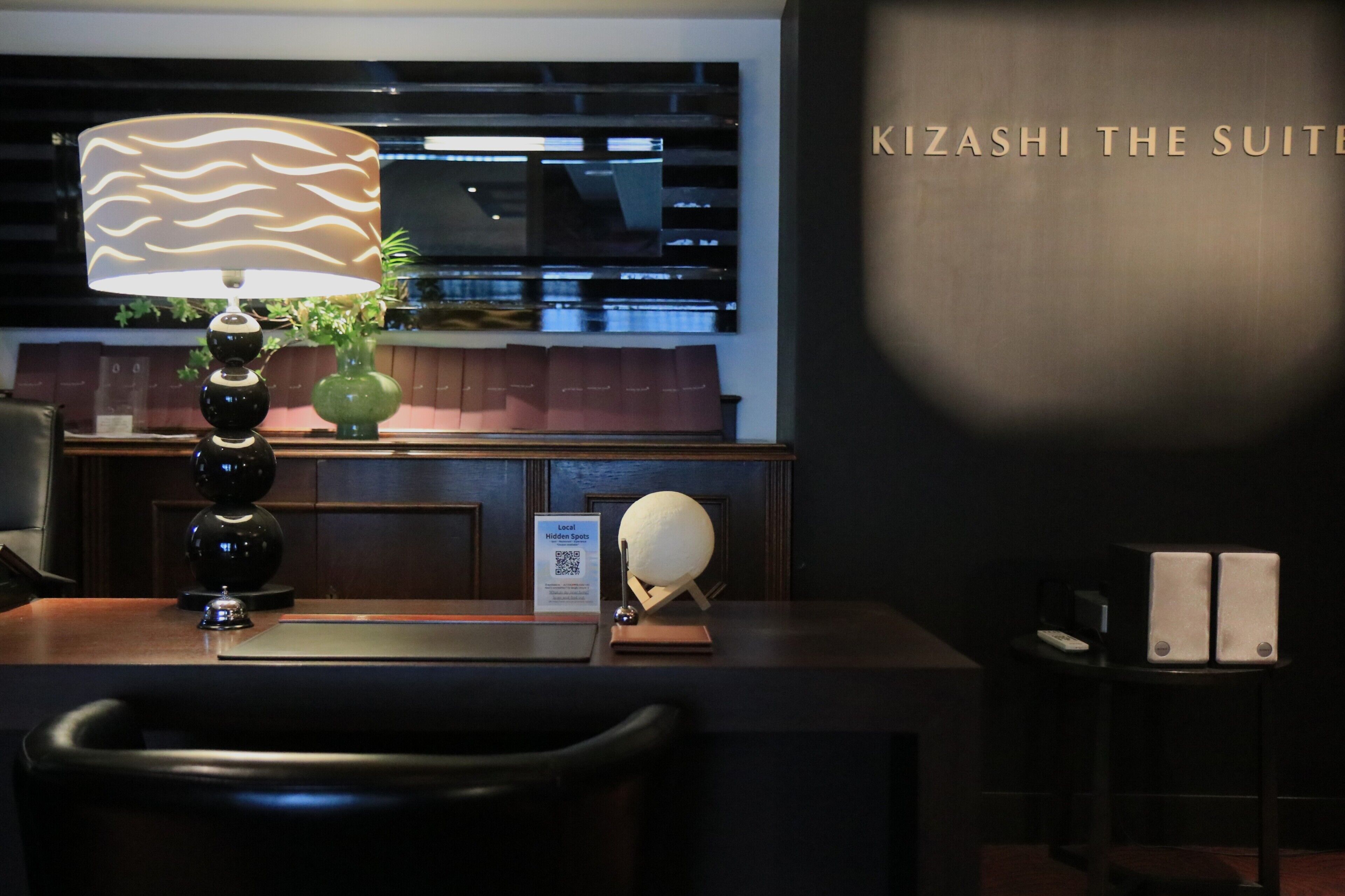 A reception desk with a lamp, a vase with plants, and a sign indicating 'Local Hidden Spots'.