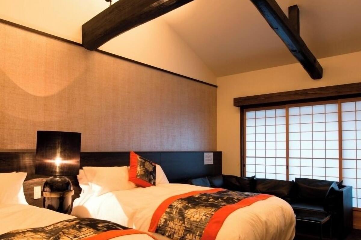 A hotel room with a large bed, a desk, and a view of the outside through a window.