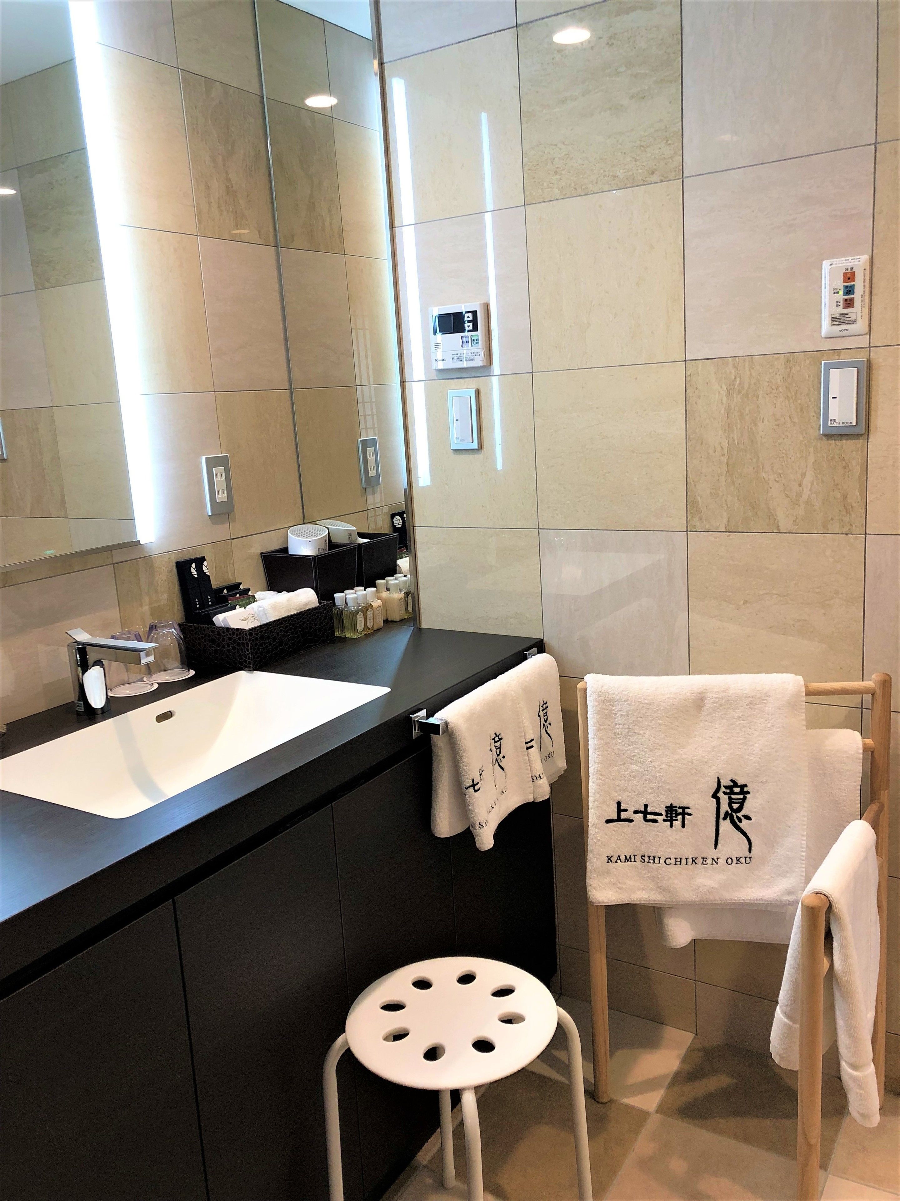 A modern bathroom with a large mirror, a sink, and a towel rack.