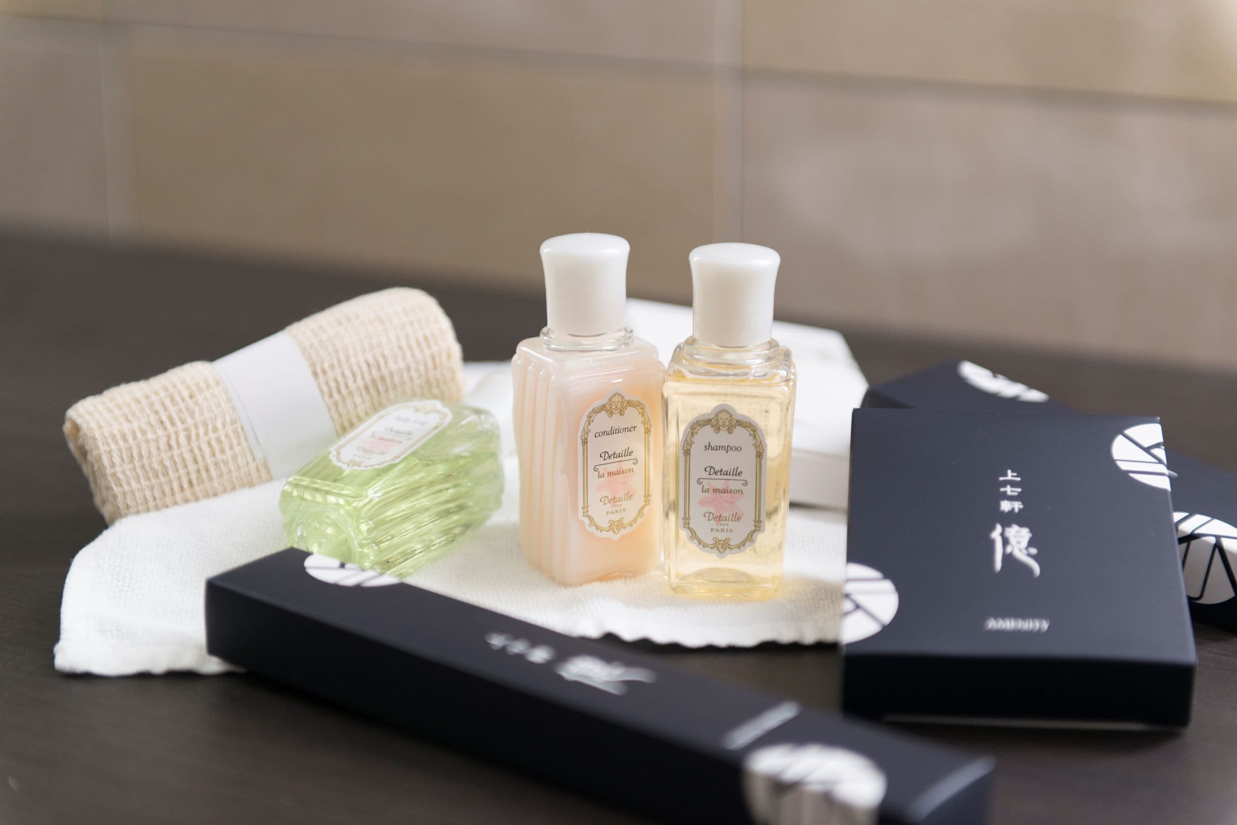 Un plateau contenant deux flacons d’après-shampoing et de shampoing, un flacon vert et une boîte noire avec du texte blanc.