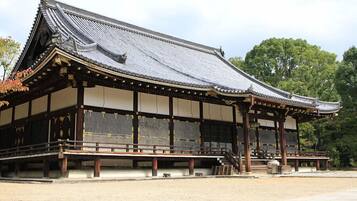 A traditional Japanese building with a curved roof, wooden beams, and a stone pathway leading to it.