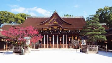 A traditional building with a tiled roof, a central entrance with a decorative arch, and a small shrine-like structure to the right.