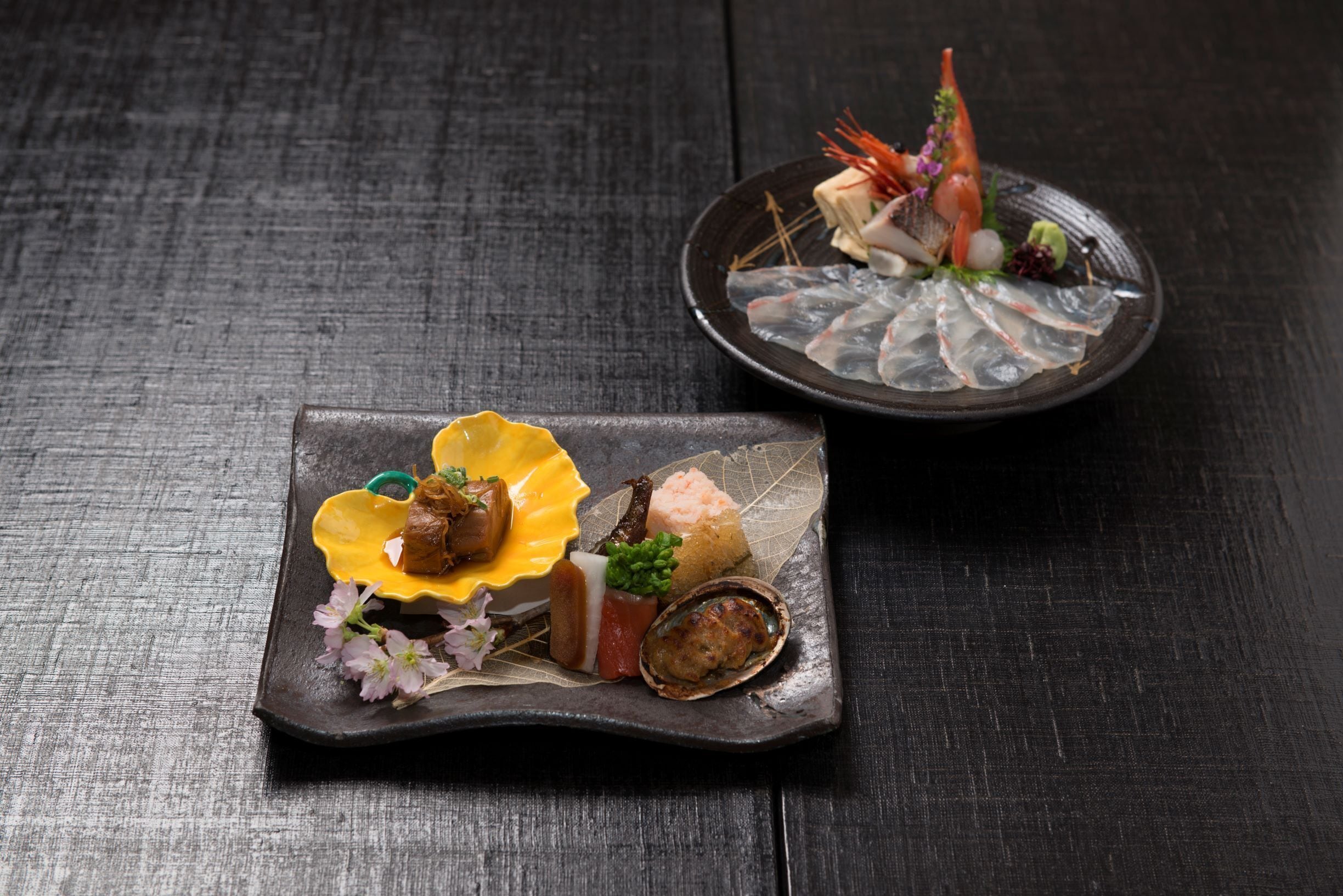 Duas porções de sushi sobre uma mesa de madeira escura.