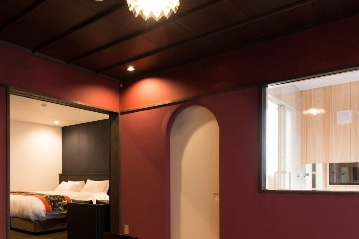 Ett modernt hotellrum med ett matbord i trä, en säng med vita sängkläder och ett stort fönster.