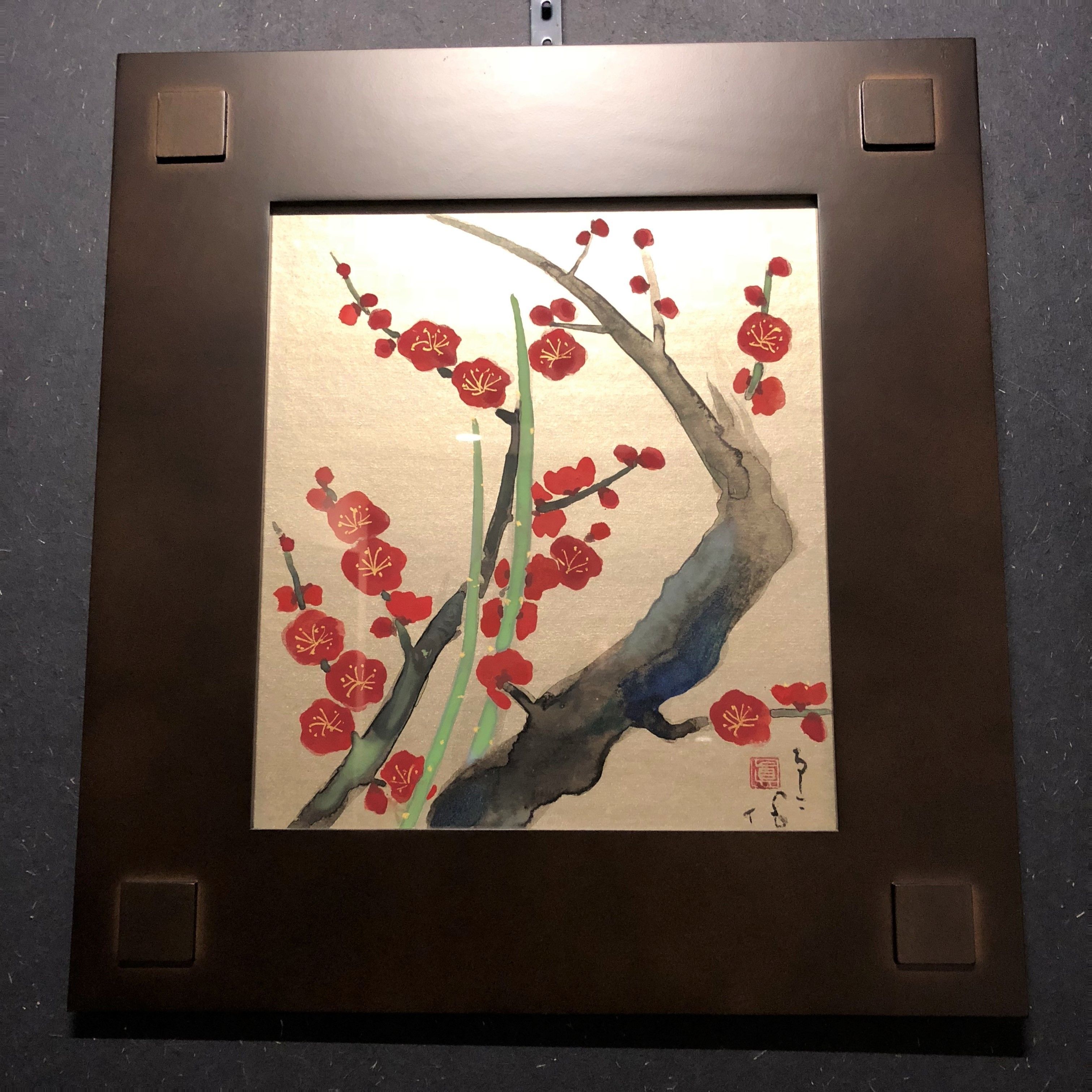 Un'opera d'arte incorniciata raffigura un albero con fiori rossi.