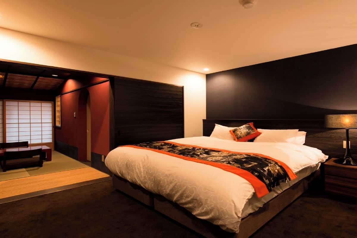 A modern hotel room with a large bed, bedside table, and a traditional Japanese sliding door.