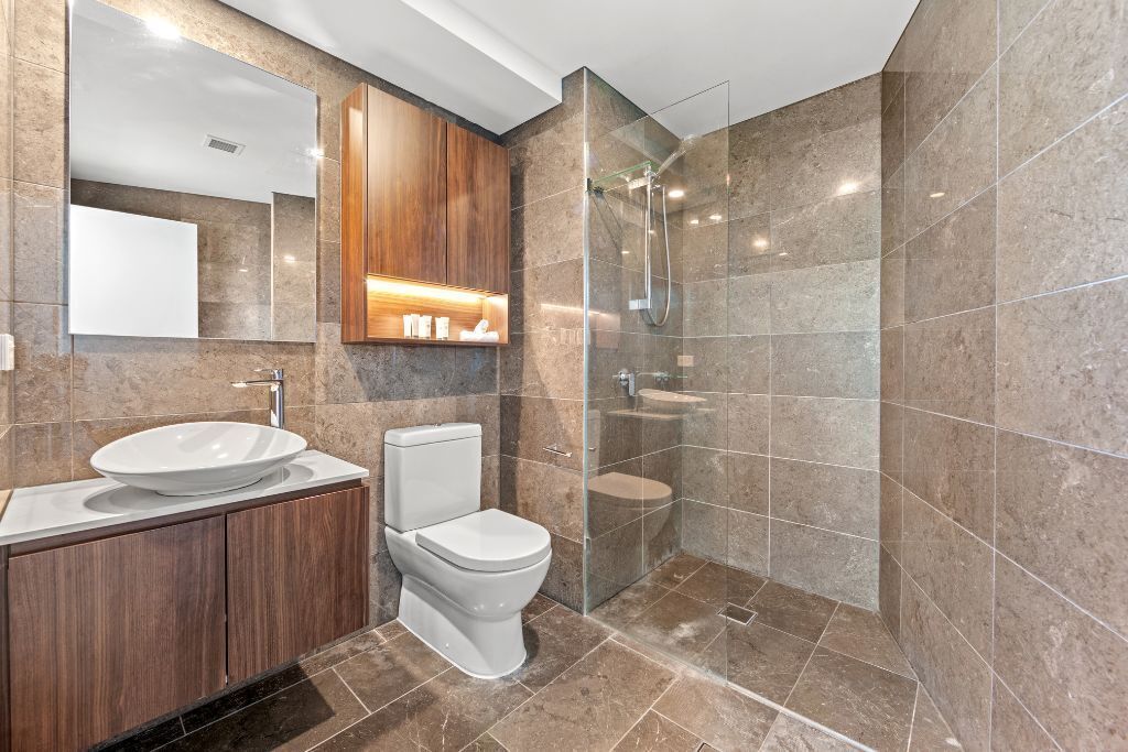 A modern bathroom with a large sink, toilet, and glass-enclosed shower.