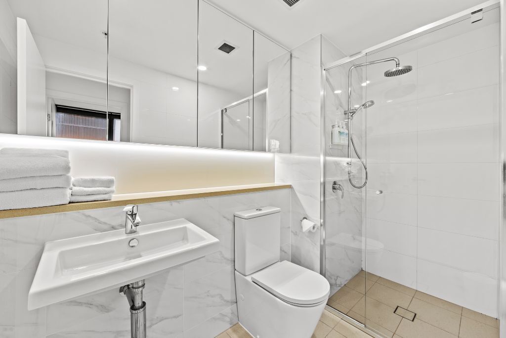 Une salle de bain moderne avec une douche à parois de verre, un lavabo blanc et des toilettes.