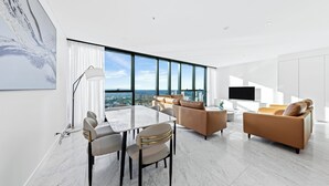 A modern living room with a dining area, large windows, and a view of the city. - CLLIX Brisbane Skytower Apartments (Brisbane)