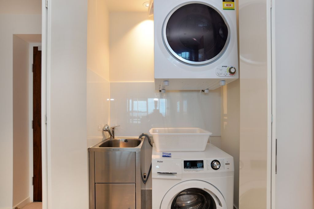 Un área de lavandería compacta con lavadora, secadora y lavabo.