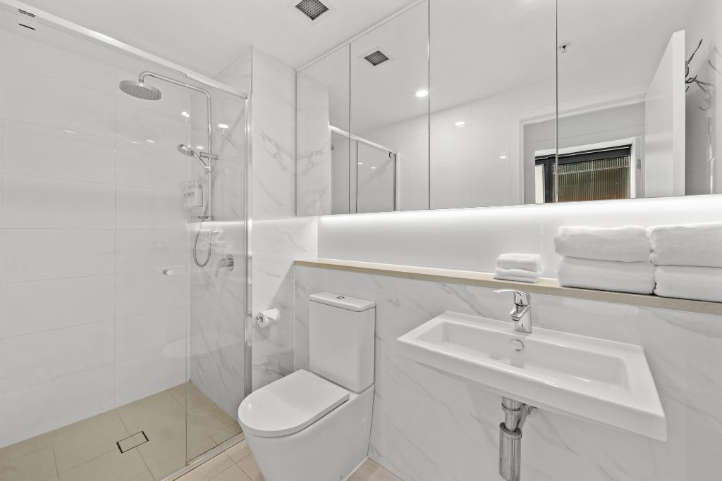 Une salle de bain moderne avec une douche à parois de verre, des toilettes et un lavabo.
