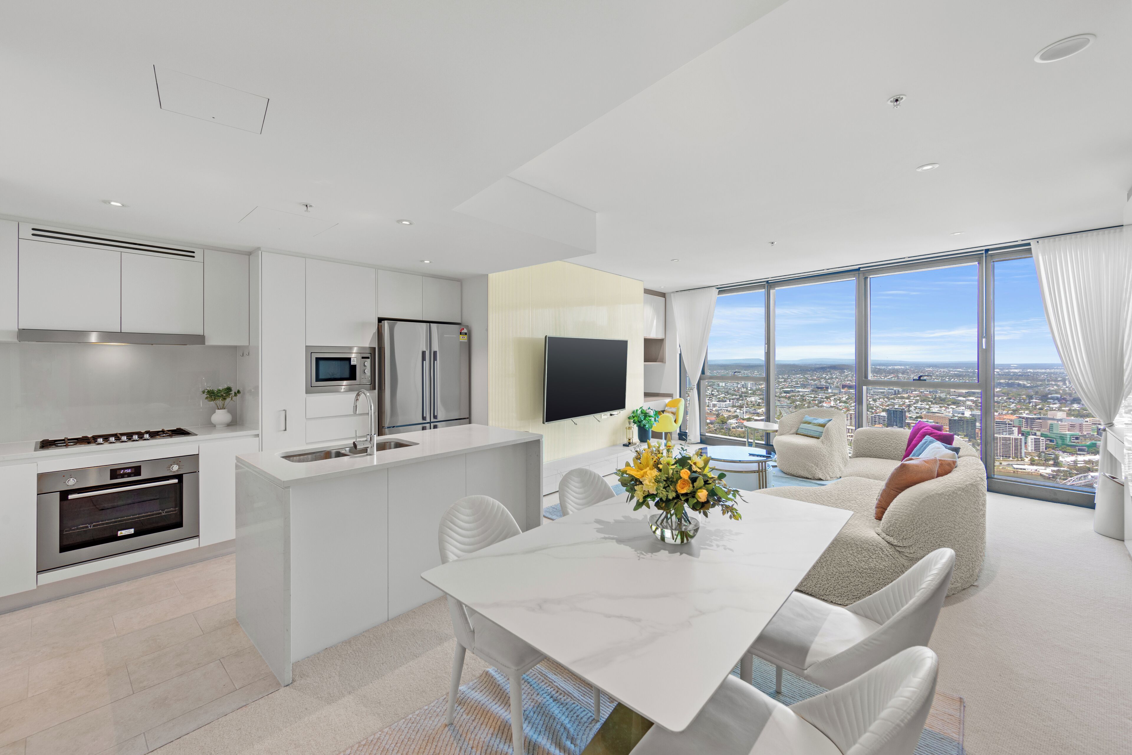 A modern kitchen with white cabinetry, a built-in oven, and a stainless steel refrigerator.