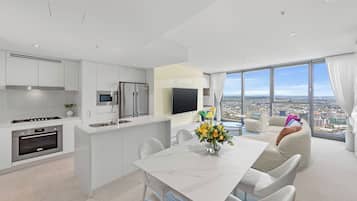 A modern kitchen with white cabinetry, a built-in oven, and a stainless steel refrigerator.