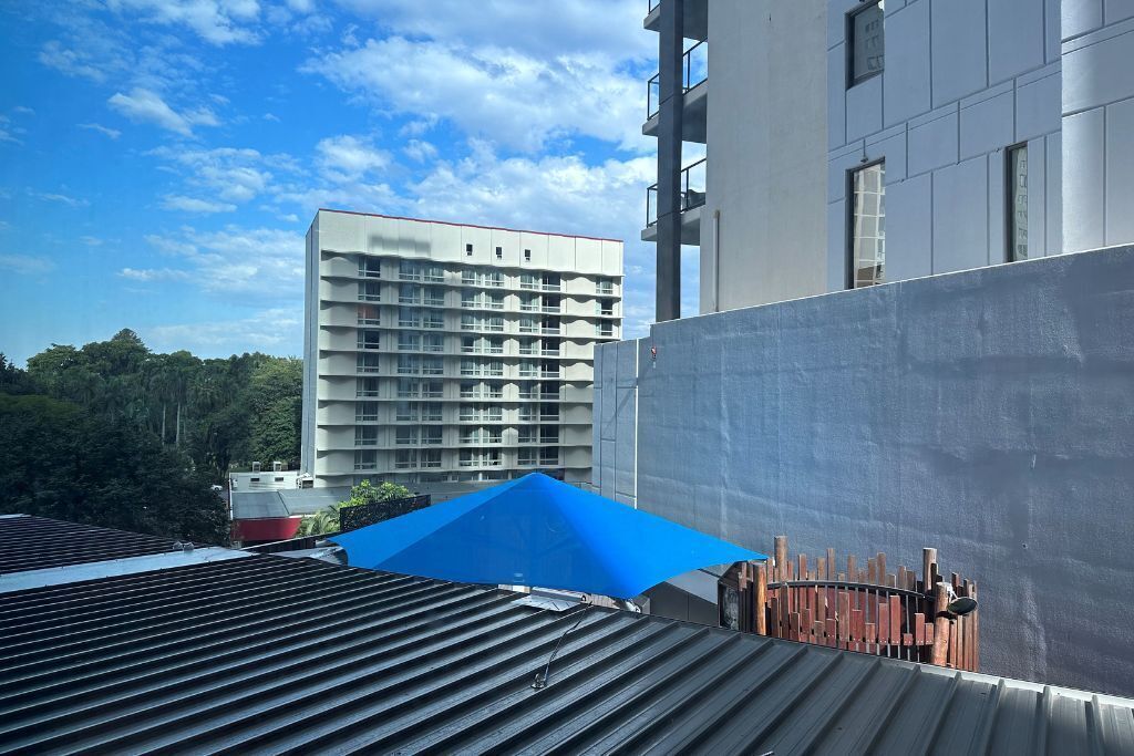 A multi-story building with a flat roof and a blue awning.