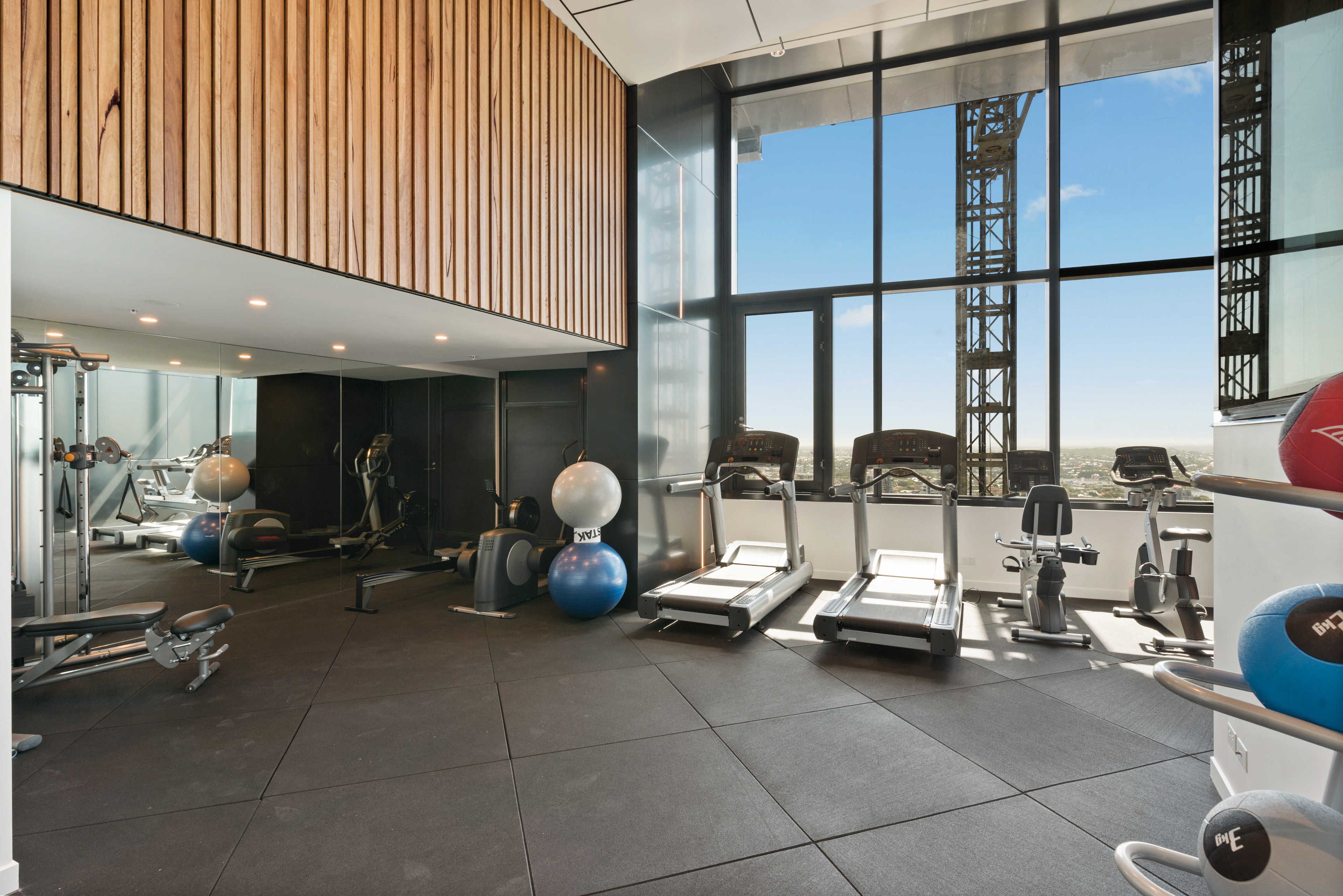 Un gimnasio moderno con diversos equipos de ejercicio, amplias ventanas y un techo alto.