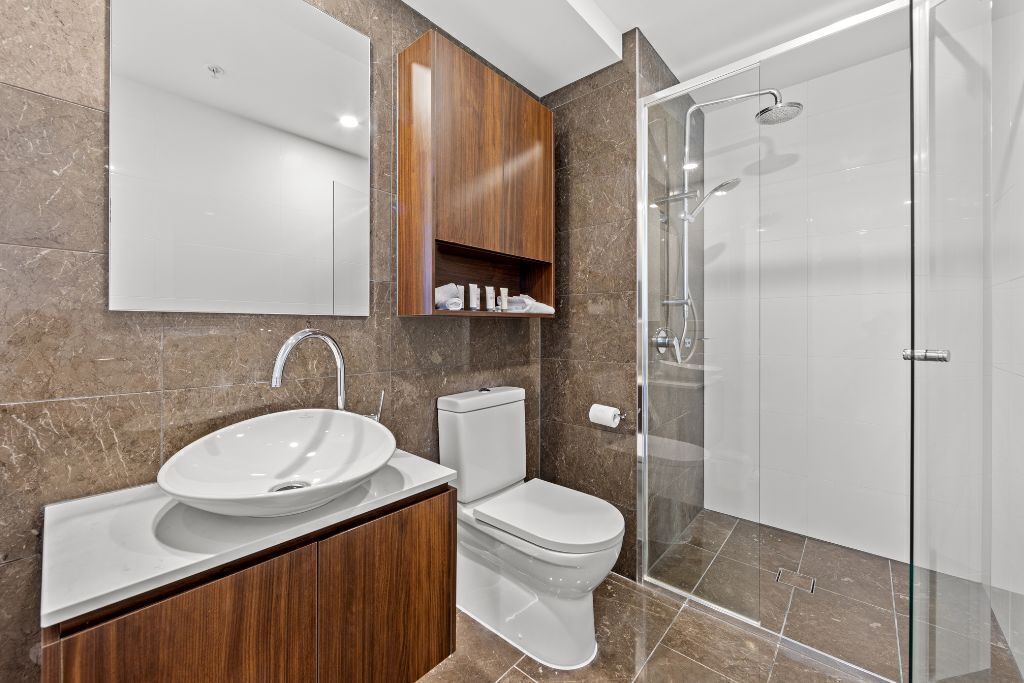Une salle de bain moderne dotée d’un grand lavabo, de toilettes et d’une douche à parois de verre.