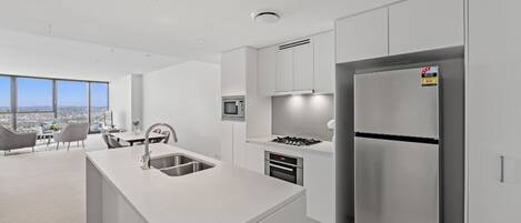 Una cocina moderna con una isla central, electrodomésticos de acero inoxidable y vistas a la ciudad.