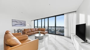 A modern living room with a large window, a flat-screen TV, and a sofa. - CLLIX Brisbane Skytower Apartments (Brisbane)