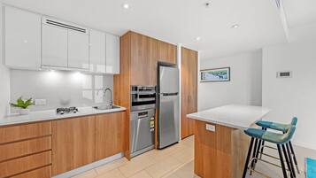 Una cocina moderna con gabinetes de madera, electrodomésticos de acero inoxidable y encimera blanca.