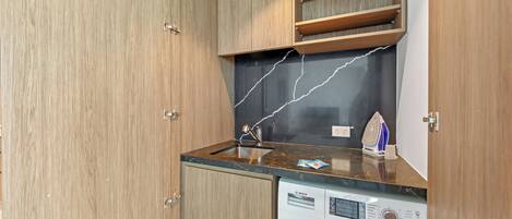 Una cocina compacta con armarios de madera, un lavamanos integrado y una lavadora Bosch.