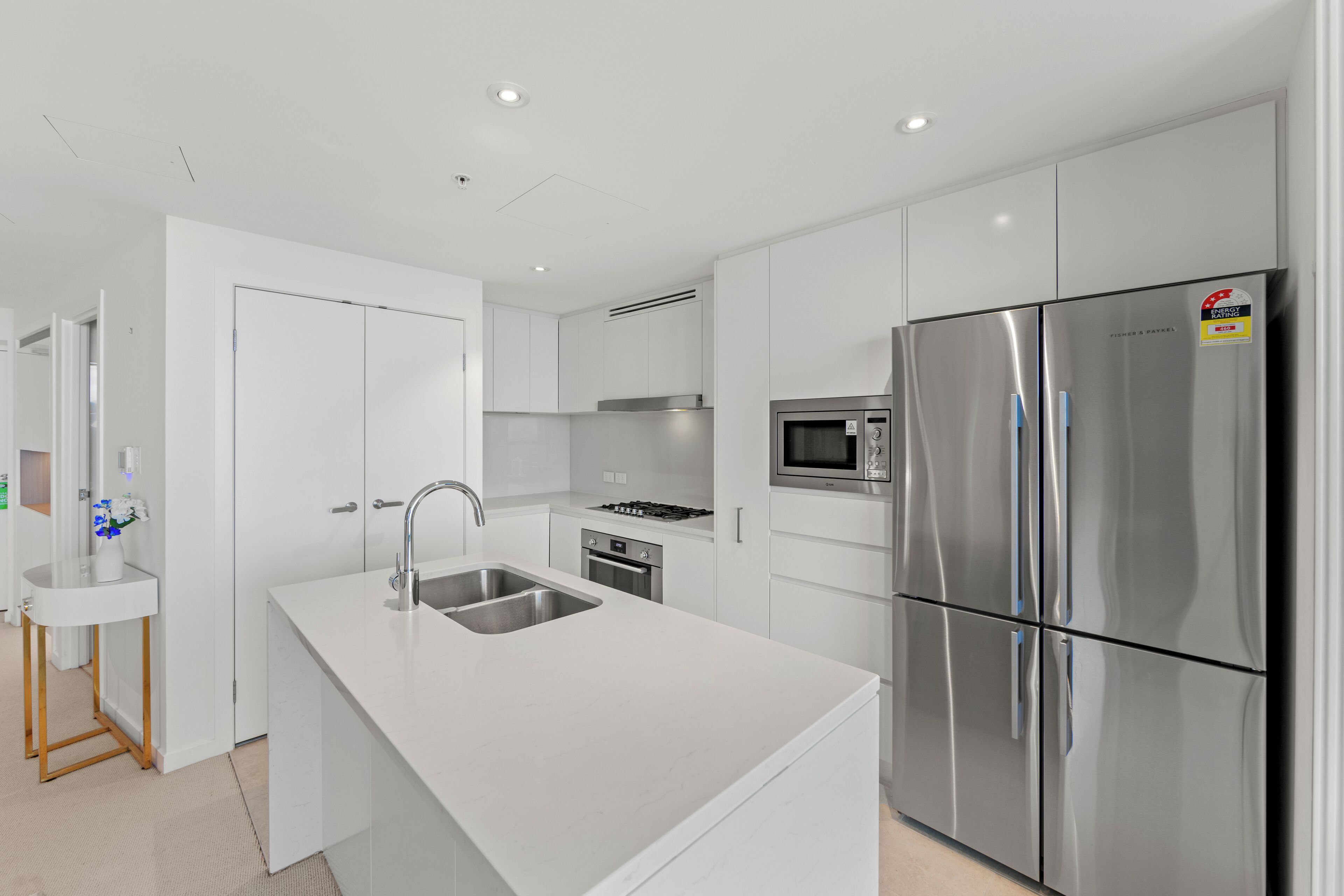 A modern kitchen with white cabinetry, stainless steel appliances, and a central island with a sink.