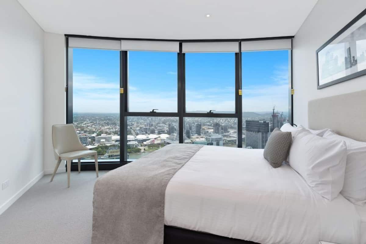 A bedroom with a large window offering a city view.
