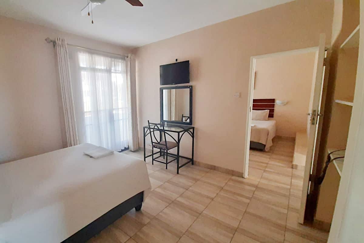 Une chambre d’hôtel comprenant un lit, un bureau avec une chaise, une télévision et une porte donnant sur une autre pièce.