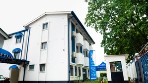 A multi-story building with a white facade and blue accents, featuring balconies and a gated entrance. - Horizon Inn (Harare)