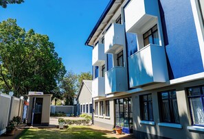 A modern building with a flat roof, large windows, and a well-maintained garden area.