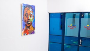 A hotel interior with a staircase, a painting on the wall, and a blue glass door with "Horizon Inn" signage. - Horizon Inn (Harare)