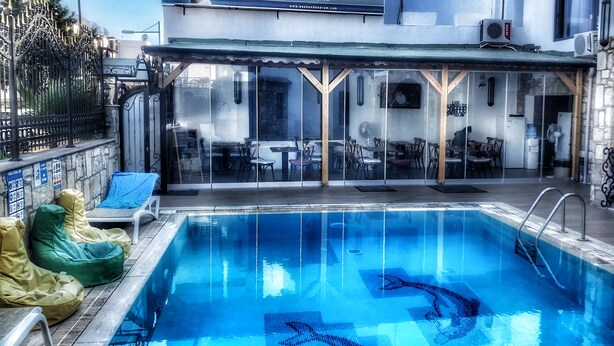 A pool area with a clear view of the pool, lounge chairs, and a restaurant with outdoor seating. - Wb Weekend Otel  (Bodrum)